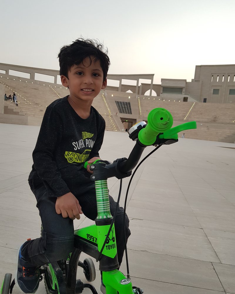 Young Zohan riding his green scooter
